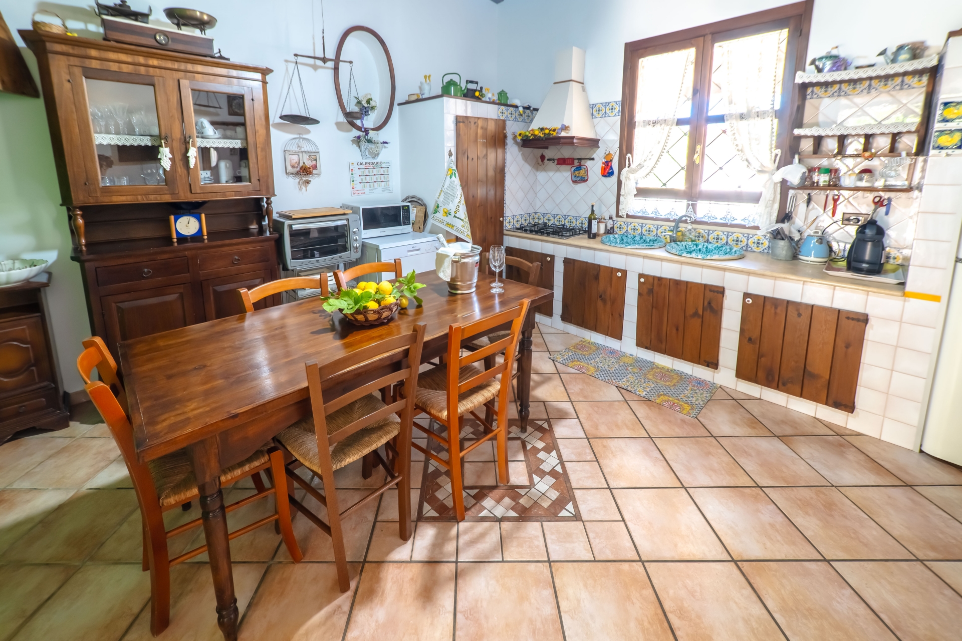Cucina con tavolo in legno, ceramiche siciliane e credenza