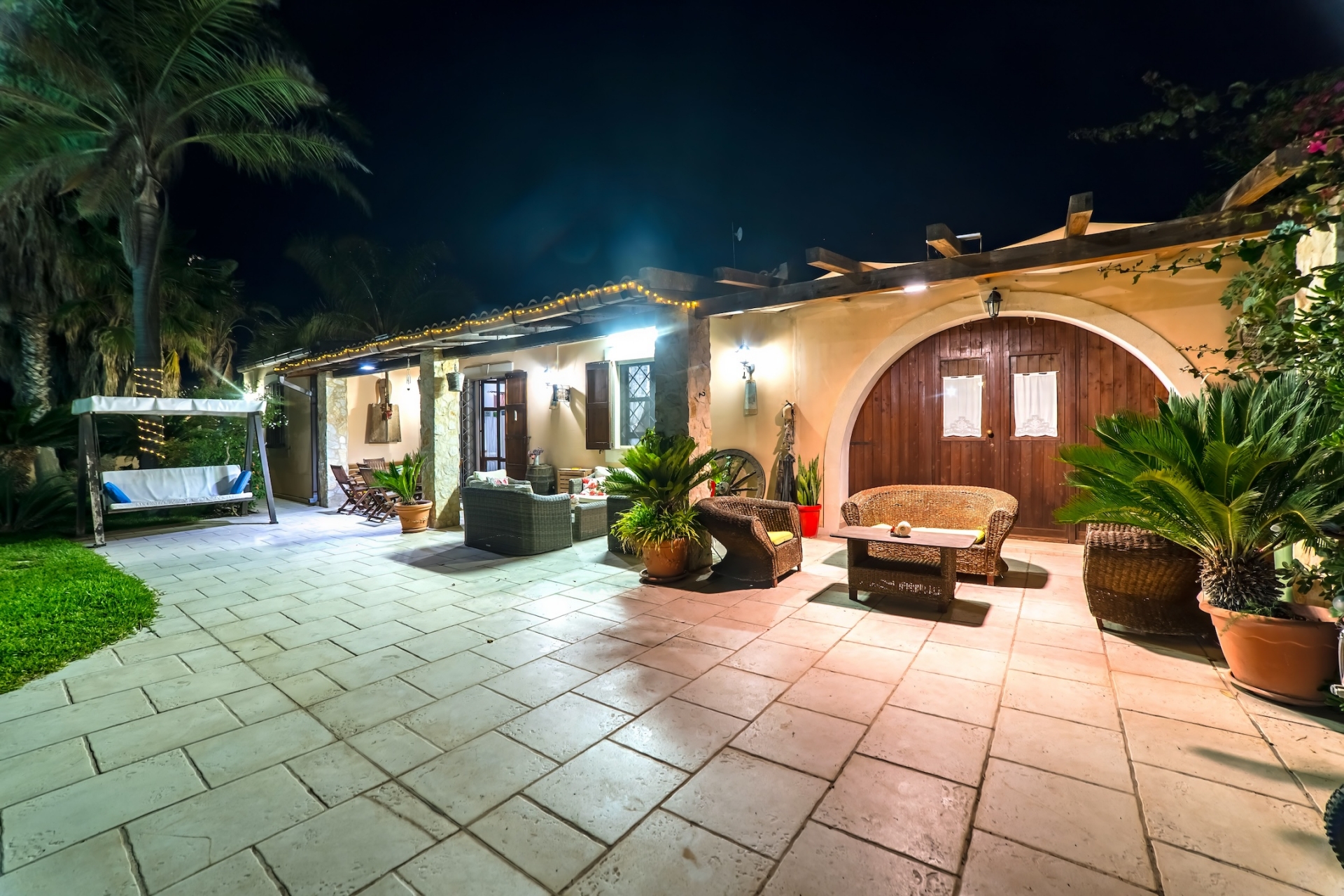 Corte d'ingresso con veranda, dondolo e portone ad arco in legno