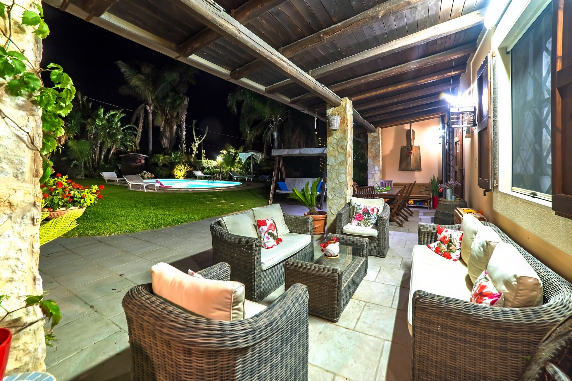 Veranda con divani in vimini affacciata sulla piscina di sera